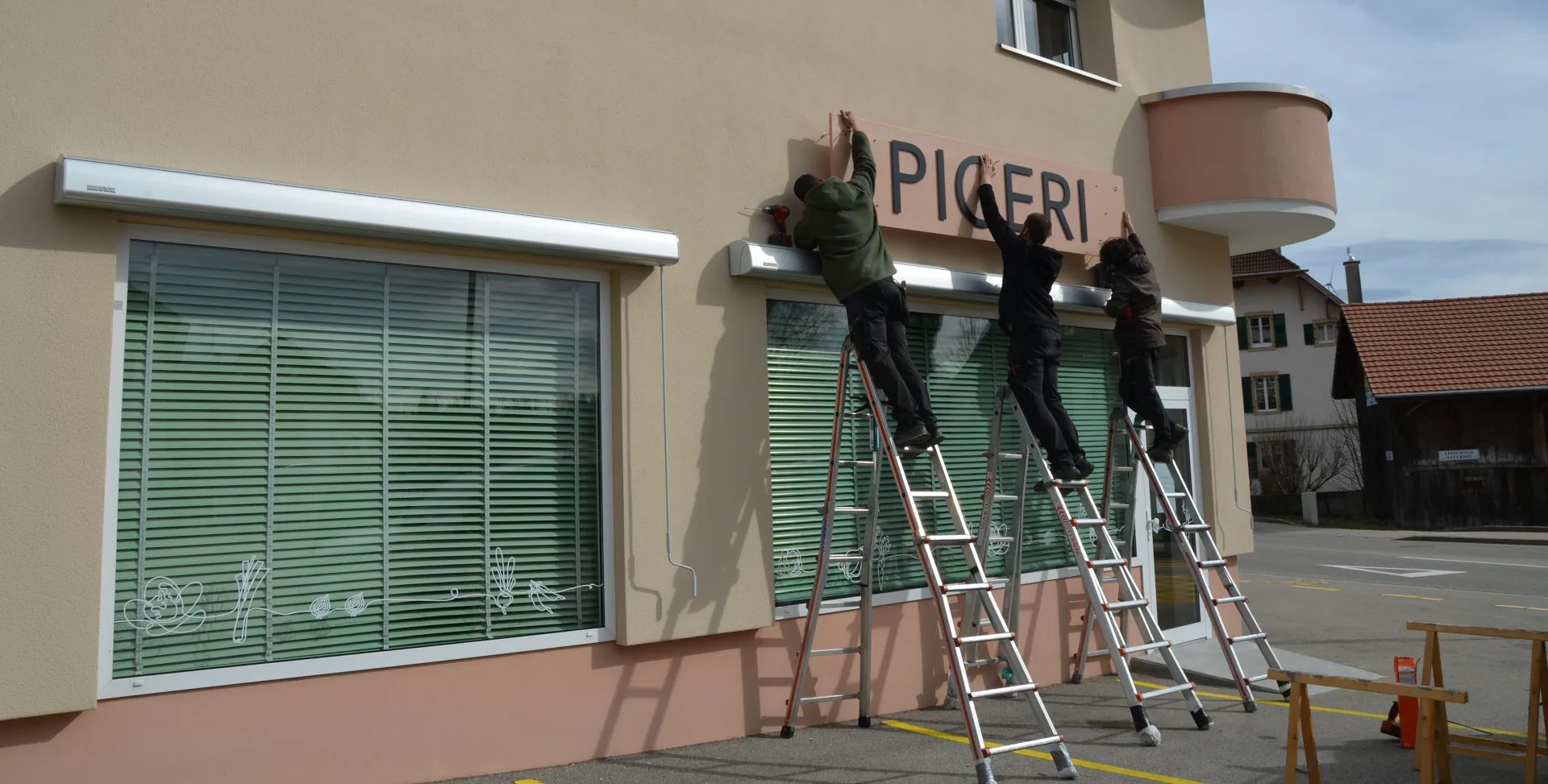 Pose de l'enseigne de l'épicerie le Noirmont